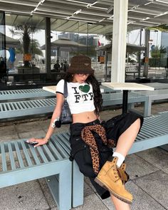 Woman in a crop top, cargo pants, and bucket hat sitting outdoors