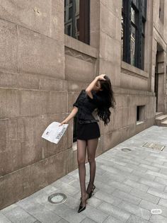 Woman in a black mini skirt and tights posing on a city street