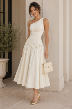 Woman in an elegant cream one-shoulder midi dress and gold heels outdoors