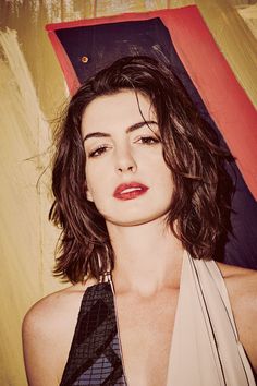 Woman with short brown hair and red lipstick against a painted background
