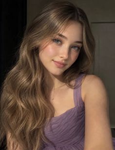 Woman with long blonde hair and blue eyes wearing a purple dress and necklace