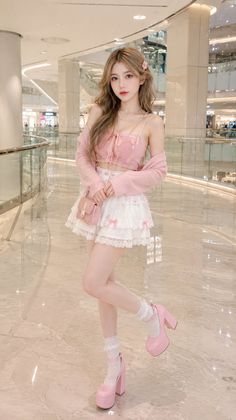 Woman in a pink top and white lace skirt with pink platform heels indoors