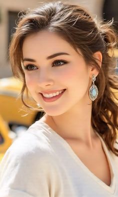 Woman with long brown hair and earrings smiling in soft lighting