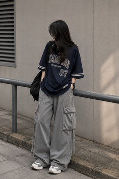 Person with long black hair wearing an oversized t-shirt and cargo pants outdoors