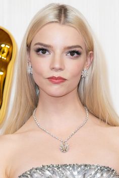 Woman with long blonde hair wearing a diamond necklace and earrings