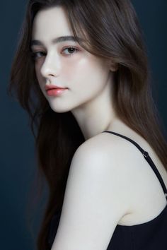 Woman with long brown hair wearing a black top against a dark background