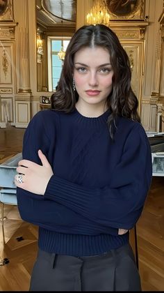 Woman with long dark hair wearing a navy blue top in an ornate room