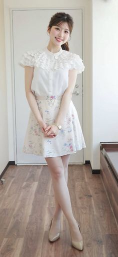 Woman in a white ruffled blouse and floral skirt smiling indoors