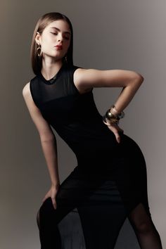 Woman in a black sheer dress with jewelry posing in a studio