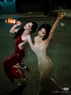 Two women in sparkly dresses posing outdoors at night
