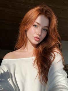 Woman with red hair and freckles wearing an off-shoulder top in soft lighting