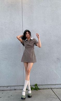 Woman in a plaid dress and mary jane shoes posing outdoors