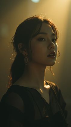 Woman with dark hair and earrings in dramatic backlight