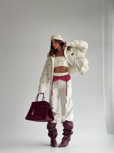 Woman in a white puffer jacket, crop top, and red garter belt with a handbag
