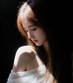 Woman with long hair and a white top, illuminated by dramatic lighting