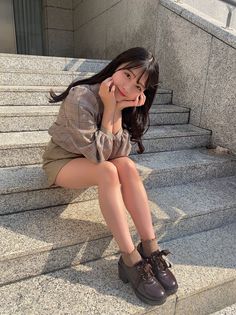 Woman with long hair sitting on outdoor stairs in a plaid shirt and mini skirt