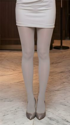 Person in a white mini skirt, white tights, and glitter high heels standing on a marble floor