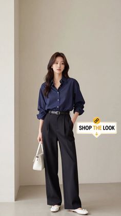 Woman in a navy blue shirt and black pants holding a white handbag