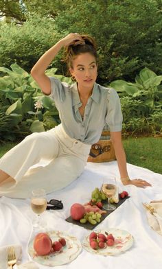 Woman in a light blue shirt and white pants having a picnic outdoors