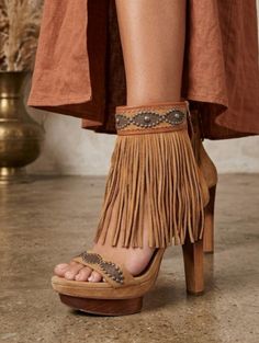 Close up of a person wearing brown fringe platform heels and a dress