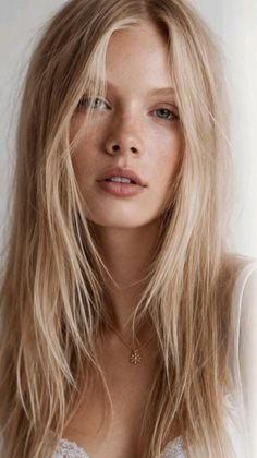 Woman with long blonde hair and freckles wearing a gold necklace