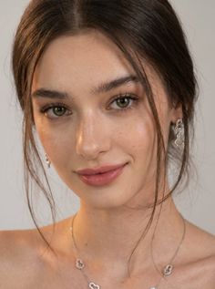 Close-up portrait of a woman with green eyes and brown hair wearing jewelry