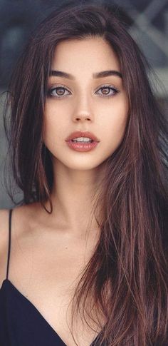 Woman with long brown hair and brown eyes wearing a top with thin straps