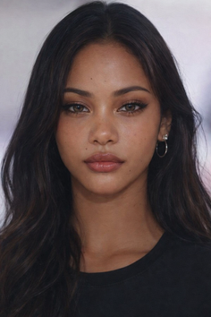 Woman with long dark hair and hoop earrings looking directly at the viewer