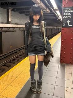 Person with long dark hair and denim shorts standing in a subway station