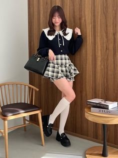 Woman in a plaid skirt and black cardigan with a ruffle collar