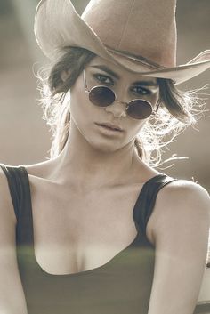 Woman in a cowboy hat and round sunglasses with backlight