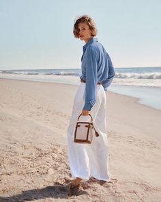 Woman in a blue shirt and white pants standing on a sandy beach