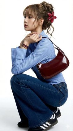 Woman in a blue striped shirt and jeans with a red flower in her hair