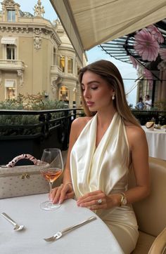 Woman in a silk dress dining outdoors with a glass of rosé wine