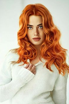 Woman with long red wavy hair and blue eyes wearing a white sweater