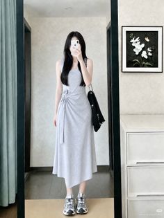 Woman in a gray dress taking a mirror selfie indoors