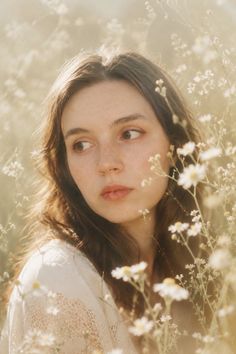 Woman with long hair and freckles in a white dress in a field of flowers