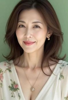 Woman with brown hair wearing a floral top and jewelry, smiling at the camera