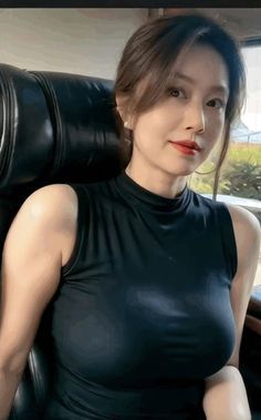Woman in a black sleeveless top with red lipstick, sitting indoors
