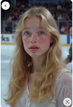 Young woman with blonde hair and blue eyes wearing a lace top at an ice rink