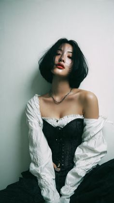 Woman with short black hair wearing a corset and white shirt, looking at the camera