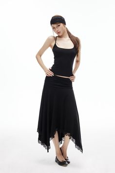 Woman in a black tank top and long skirt with lace trim on a white background