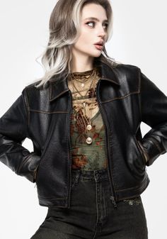 Woman in a black leather jacket and sheer top with layered necklaces