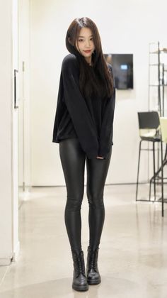 Woman in a black sweater and leather leggings with combat boots indoors