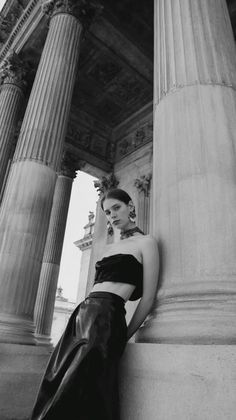 Woman in a strapless top and long skirt posing by classical columns