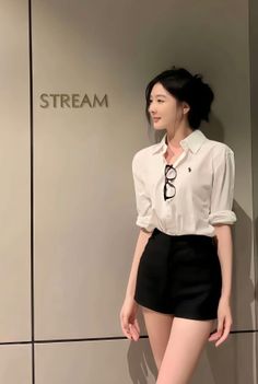 Woman in a white shirt and black shorts with glasses hanging from her collar
