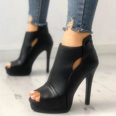 Person wearing black peep-toe ankle boots with ripped jeans