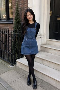 Woman in a denim dress and black tights standing on a street