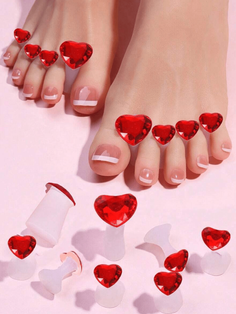 Feet with red heart toe separators and french tip pedicure on a pink background