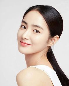 Woman with black hair in a ponytail wearing a white top, looking over her shoulder
